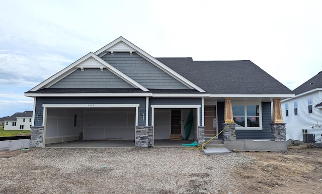 7869 41st St N, Oakdale, MN 55128 - craftsman house featuring a garage, covered porch, stone siding, driveway, and roof with shingles