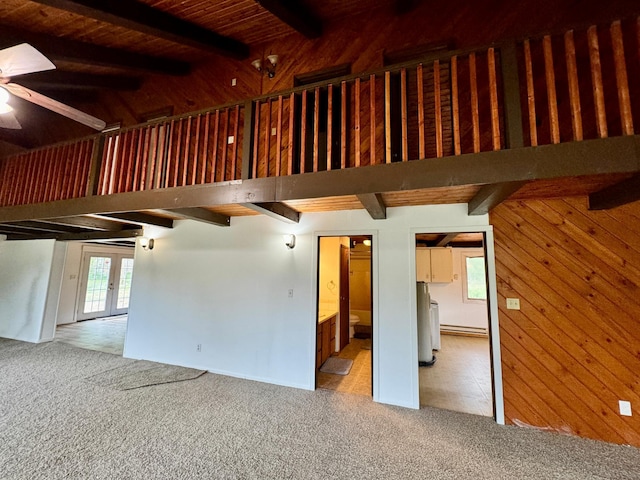 56279 350th St, Warroad, MN 56763 - unfurnished living room featuring carpet flooring, beamed ceiling, a ceiling fan, wood walls, and french doors