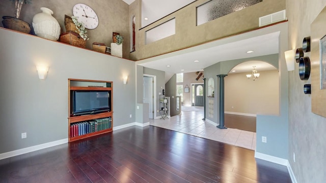 610 Main St, Adams, MN 55909 - unfurnished living room featuring decorative columns, arched walkways, wood finished floors, a towering ceiling, and baseboards