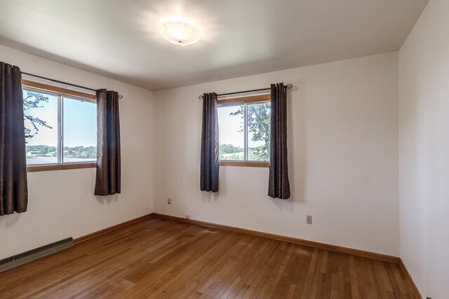 468 Washington St, Le Center, MN 56057 - spare room with a baseboard radiator, baseboards, healthy amount of natural light, and wood-type flooring