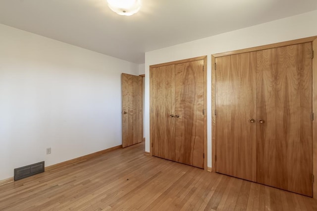 468 Washington St, Le Center, MN 56057 - unfurnished bedroom with two closets, wood finished floors, and baseboards