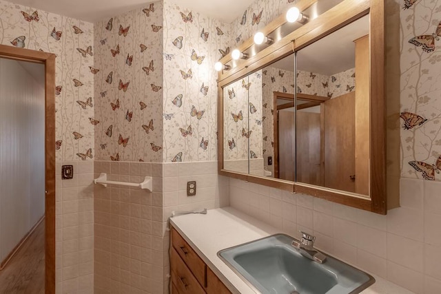 468 Washington St, Le Center, MN 56057 - bathroom featuring tile walls, vanity, wallpapered walls, and wainscoting