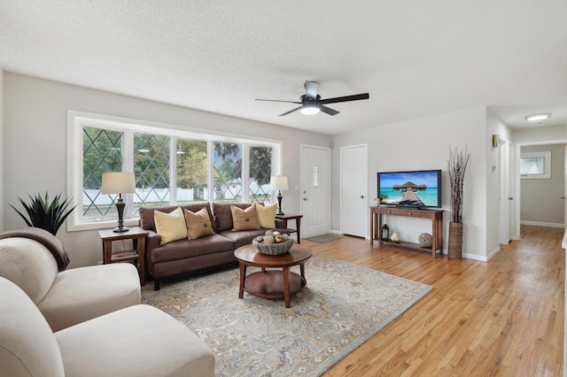 living area featuring light wood-style flooring, ceiling fan, and baseboards