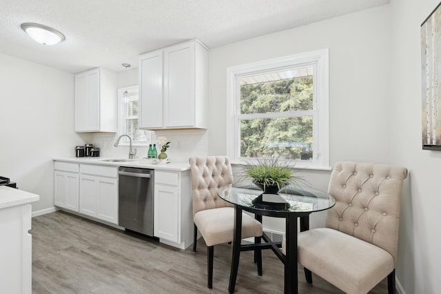 kitchen with dishwasher, a sink, light wood-style flooring, healthy amount of natural light, and a textured ceiling