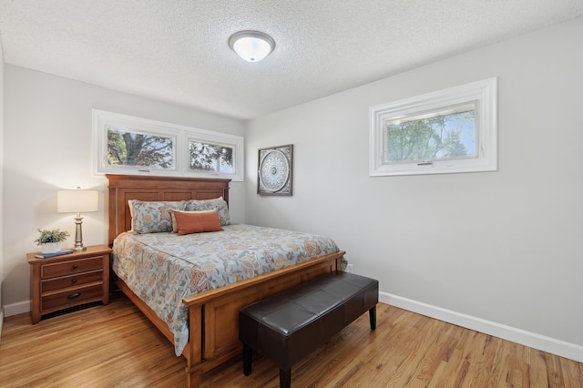 bedroom featuring baseboards, wood finished floors, and a textured ceiling