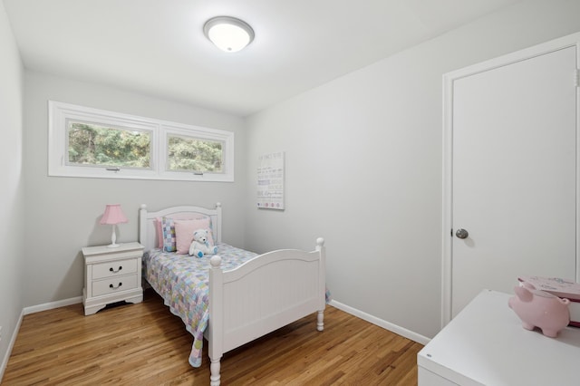 bedroom with baseboards, light wood-style flooring, and washer / dryer