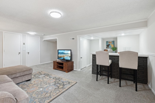 carpeted living room with a textured ceiling, a dry bar, baseboards, and ornamental molding