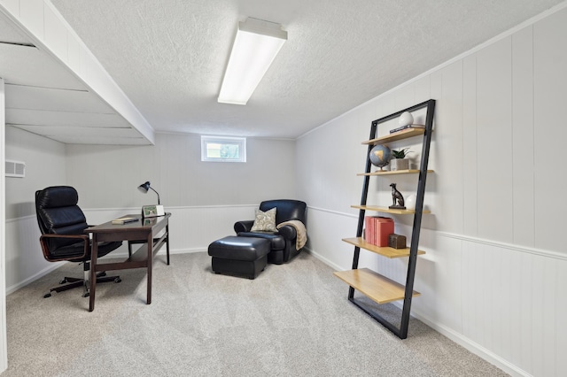 office area with a textured ceiling, a decorative wall, and carpet flooring