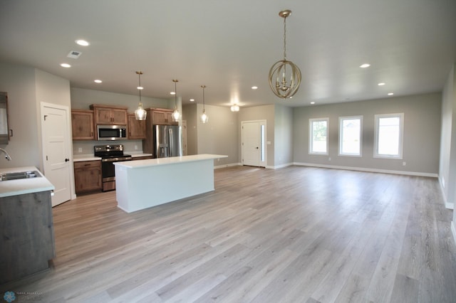 kitchen featuring stainless steel appliances, a sink, recessed lighting, a kitchen island, and a chandelier