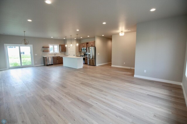unfurnished living room with baseboards, light wood-style floors, a sink, and recessed lighting