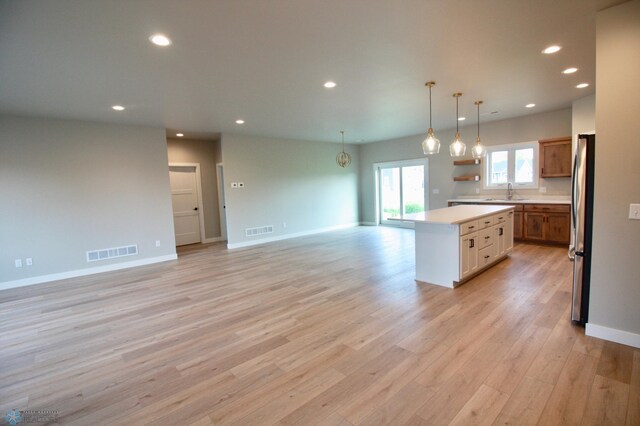 kitchen with freestanding refrigerator, a kitchen island, open floor plan, light countertops, and recessed lighting