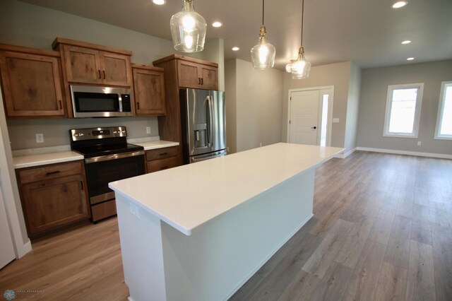 kitchen with stainless steel appliances, light wood finished floors, light countertops, recessed lighting, and a center island