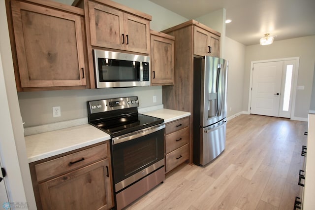 kitchen featuring stainless steel appliances, light wood-style flooring, light countertops, baseboards, and recessed lighting