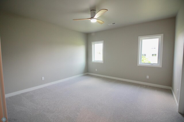spare room featuring a ceiling fan, light colored carpet, and baseboards