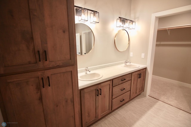 full bathroom featuring double vanity, baseboards, and a walk in closet
