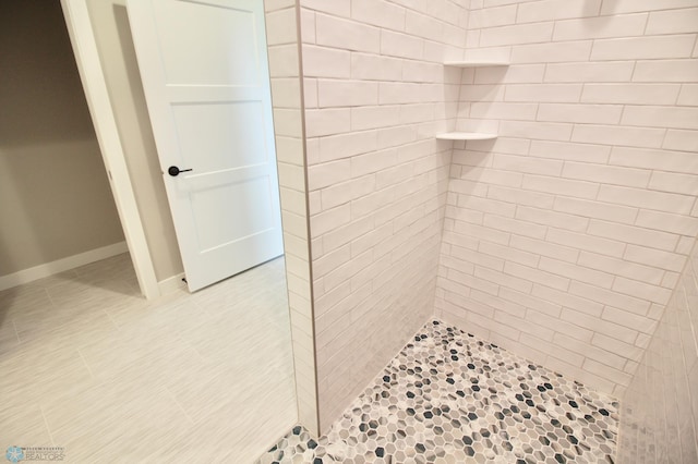 full bathroom with tiled shower and tile patterned flooring