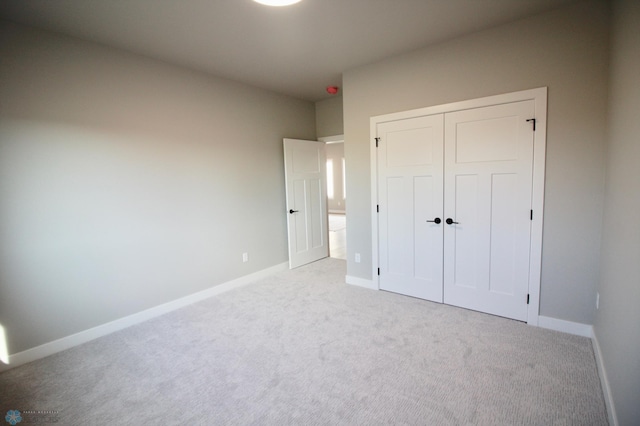 unfurnished bedroom with carpet floors, a closet, and baseboards
