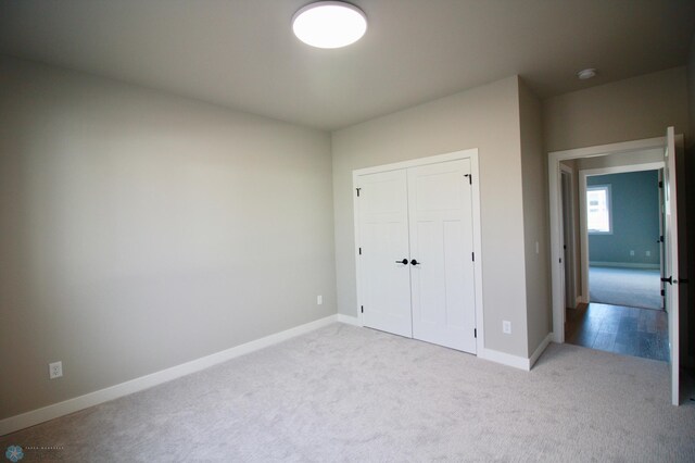 unfurnished bedroom featuring carpet, baseboards, and a closet
