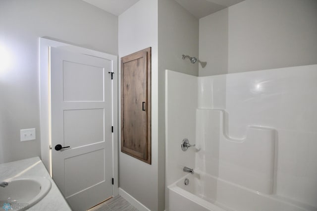 bathroom with a sink, shower / bathtub combination, and baseboards