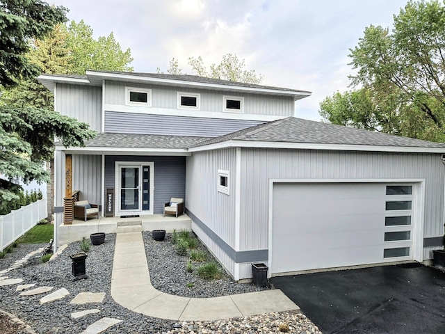 view of front of property featuring a porch, an attached garage, roof with shingles, fence, and asphalt driveway
