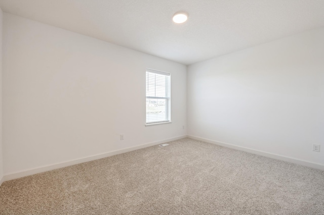 unfurnished room with light colored carpet and baseboards