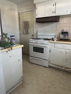 kitchen with white gas stove, under cabinet range hood, white cabinetry, and light countertops
