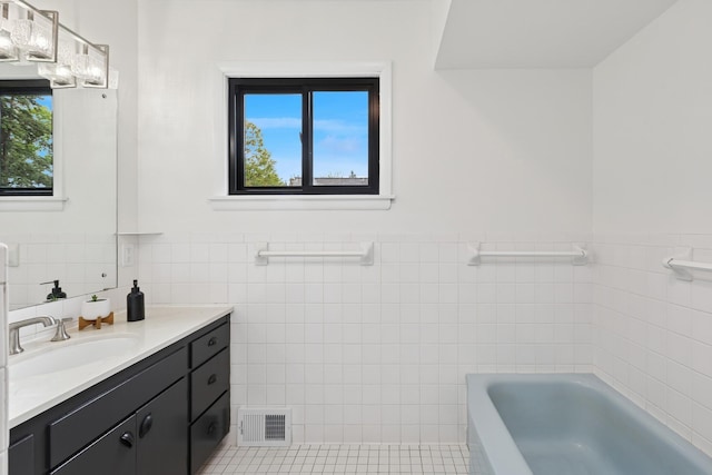 124 Paisley Ln, Golden Valley, MN 55422 - bathroom with tile walls, vanity, a tub to relax in, a wainscoted wall, and tile patterned flooring