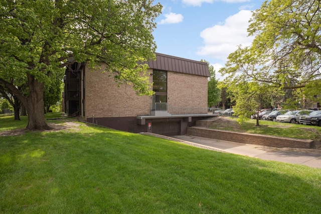 4201 Lakeside Ave N Unit 317, Brooklyn Center, MN 55429 - view of property exterior featuring a garage, a lawn, concrete driveway, and metal roof