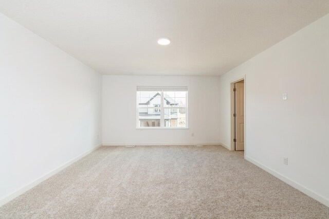 spare room featuring light carpet, baseboards, and recessed lighting
