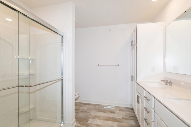 full bath featuring a stall shower, toilet, double vanity, and recessed lighting