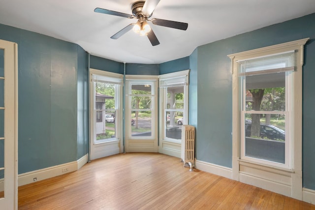 709 7th St SE, Minneapolis, MN 55414 - unfurnished room featuring radiator, hardwood / wood-style floors, a ceiling fan, and healthy amount of natural light
