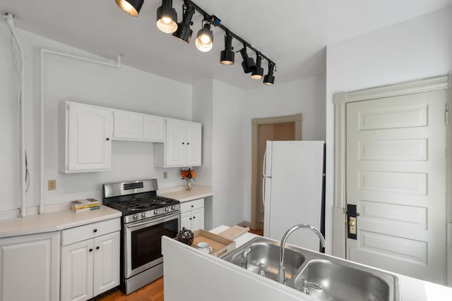 709 7th St SE, Minneapolis, MN 55414 - kitchen featuring freestanding refrigerator, stainless steel range with gas stovetop, a sink, white cabinetry, and light countertops