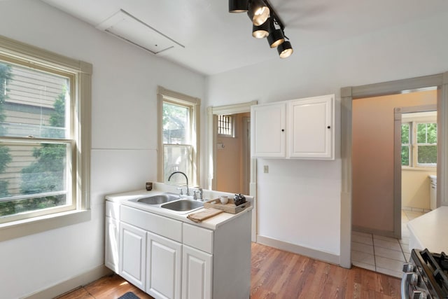 709 7th St SE, Minneapolis, MN 55414 - kitchen featuring a sink, stainless steel gas range oven, white cabinetry, light countertops, and light wood finished floors