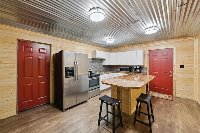 24625 Fosmo Dr, La Follette Twp, WI 54893 - kitchen featuring appliances with stainless steel finishes, white cabinets, wood walls, a breakfast bar, and a sink