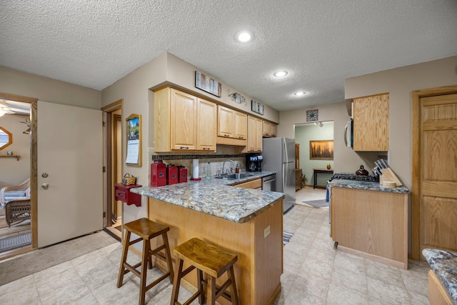 8007 5th St NE, Spring Lake Park, MN 55432 - kitchen with appliances with stainless steel finishes, a sink, a peninsula, a textured ceiling, and light brown cabinets