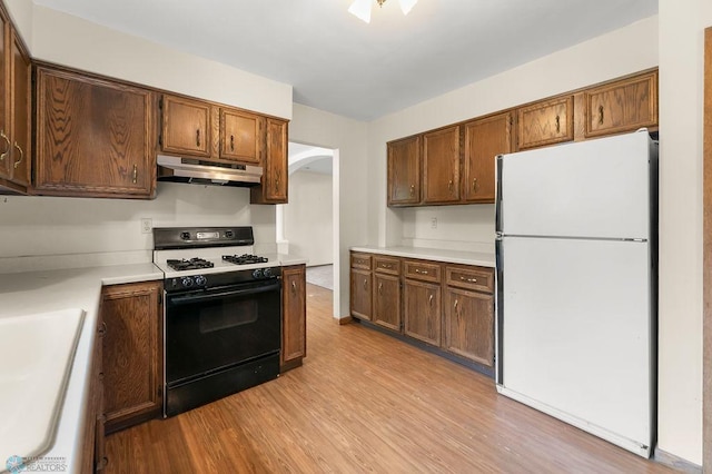 3667 Evergreen Rd N, Fargo, ND 58102 - kitchen with freestanding refrigerator, range with gas stovetop, under cabinet range hood, light wood-style floors, and arched walkways
