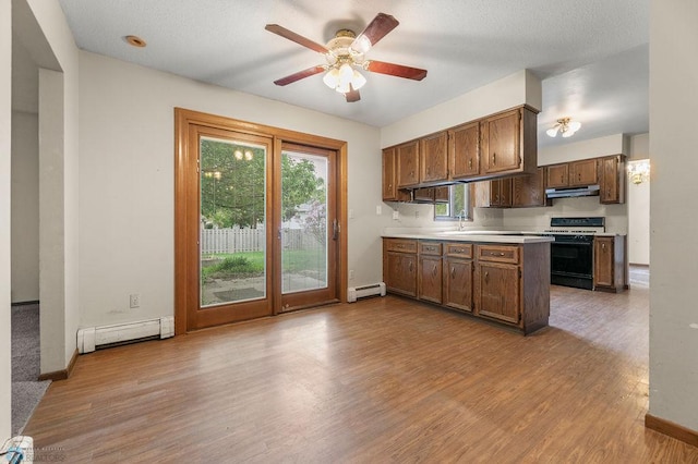 3667 Evergreen Rd N, Fargo, ND 58102 - kitchen with gas range oven, under cabinet range hood, baseboard heating, light countertops, and wood finished floors