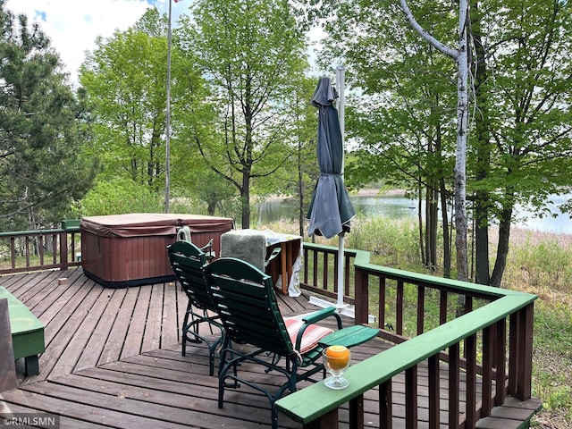 deck with a hot tub, a water view, and outdoor dining area