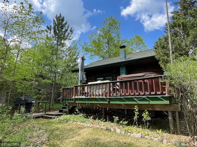 back of property with a deck, a chimney, and roof with shingles