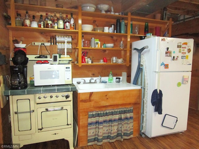 kitchen with white appliances, wood finished floors, and a sink