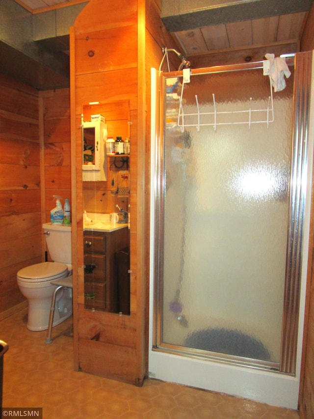 full bathroom with wooden walls, a shower stall, toilet, and vanity