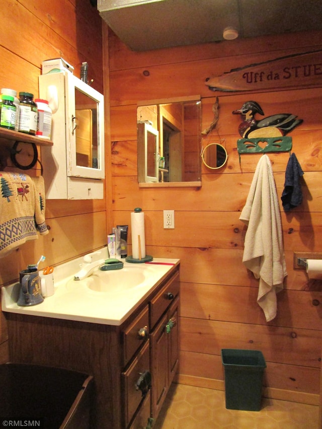 bathroom with wooden walls, vanity, and tile patterned flooring