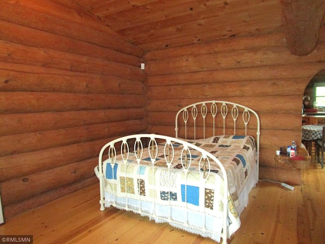 bedroom featuring hardwood / wood-style flooring, arched walkways, wooden ceiling, and vaulted ceiling