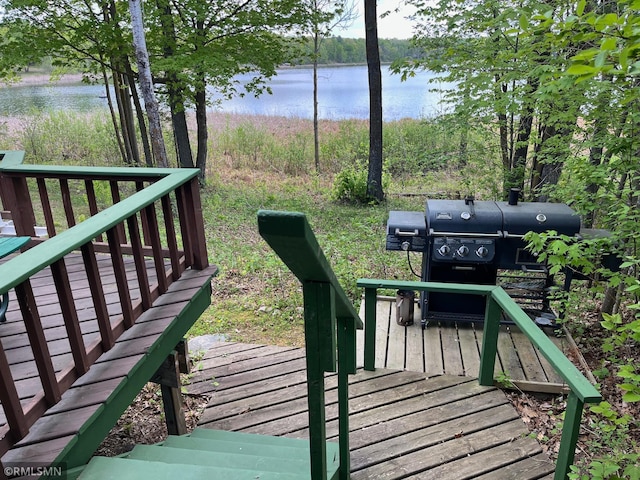 wooden deck featuring a water view and a grill
