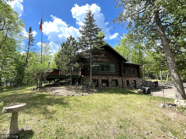 back of property featuring log exterior, a yard, stone siding, and a wooden deck
