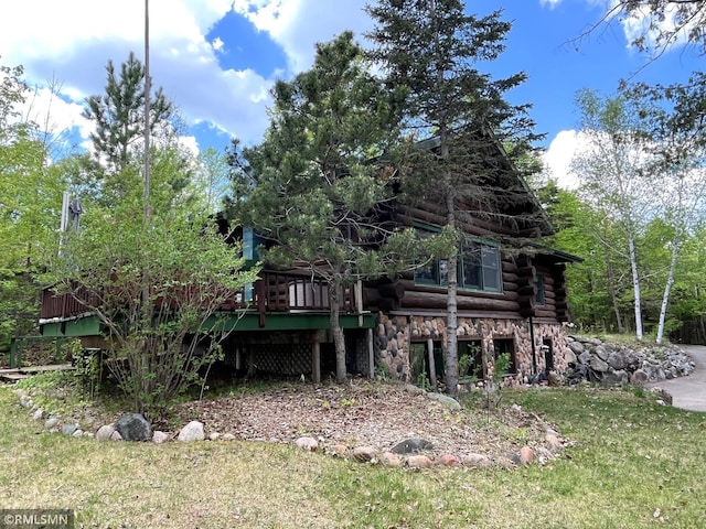 rear view of property featuring log siding, a wooden deck, a lawn, and stone siding