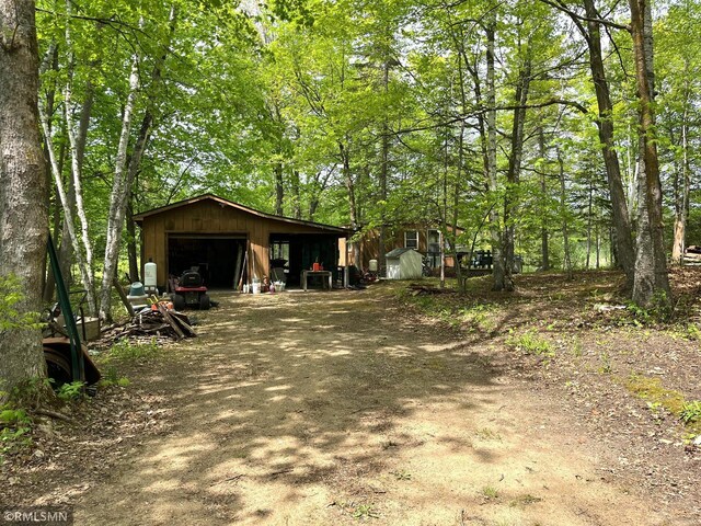 view of side of home with an outdoor structure, a detached garage, and dirt driveway
