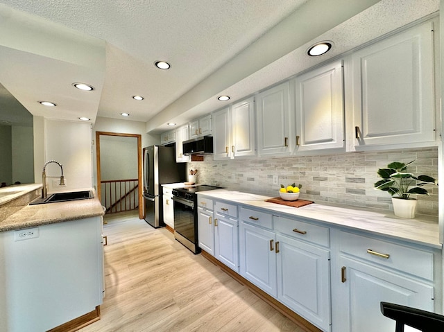 kitchen with a sink, appliances with stainless steel finishes, decorative backsplash, light wood-style floors, and recessed lighting