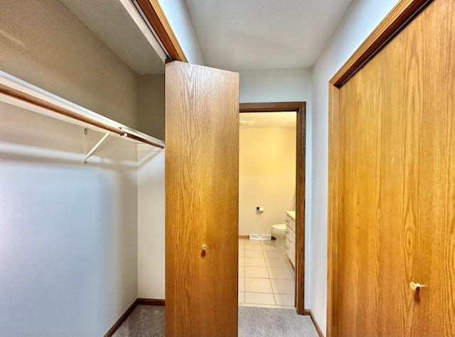 walk in closet with carpet floors and tile patterned floors