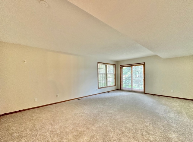 empty room featuring light colored carpet and baseboards